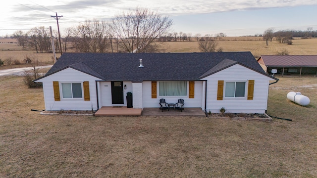 ranch-style home with a patio area, a front lawn, and a rural view