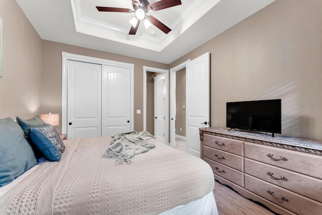 bedroom featuring a raised ceiling, ornamental molding, a closet, and ceiling fan