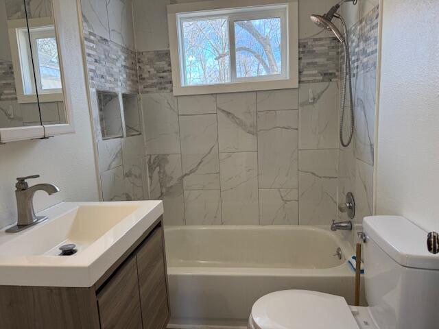 full bathroom with vanity, toilet, tiled shower / bath combo, and a wealth of natural light