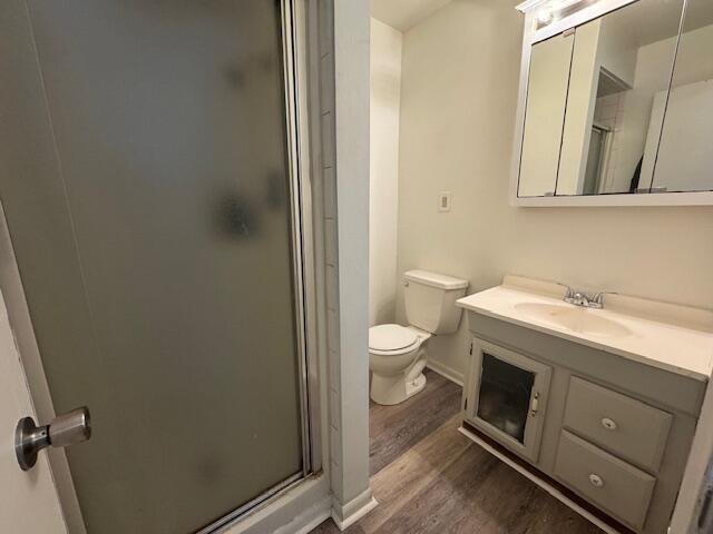 bathroom with vanity, hardwood / wood-style floors, an enclosed shower, and toilet