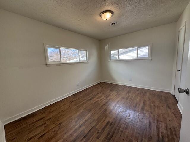 spare room featuring dark wood-type flooring and a textured ceiling