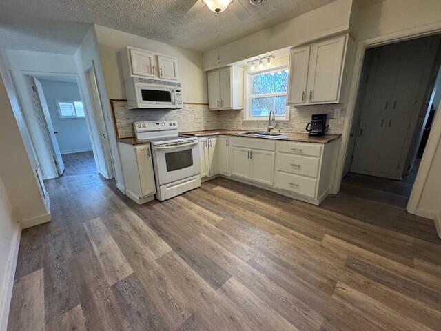 kitchen featuring sink, white appliances, hardwood / wood-style flooring, backsplash, and white cabinets