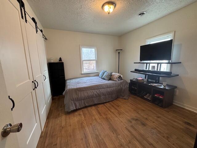 bedroom with dark hardwood / wood-style floors, a barn door, and a textured ceiling