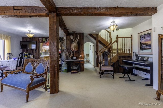 interior space with beamed ceiling, carpet, a textured ceiling, and ornate columns