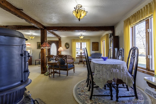 carpeted dining area with beam ceiling and a textured ceiling