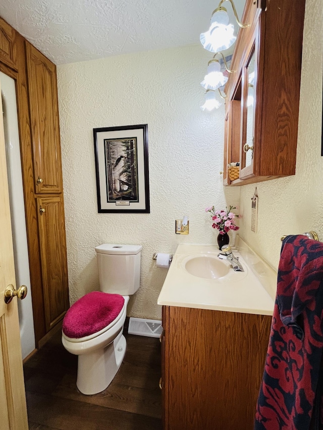 bathroom with hardwood / wood-style flooring, vanity, toilet, and a textured ceiling