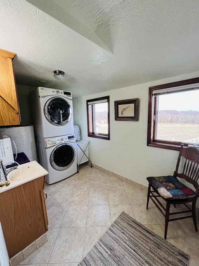 laundry room with cabinets, stacked washing maching and dryer, a textured ceiling, and light tile patterned floors