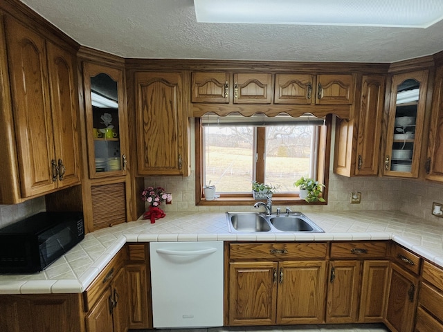 kitchen with sink, tasteful backsplash, white dishwasher, a textured ceiling, and tile countertops