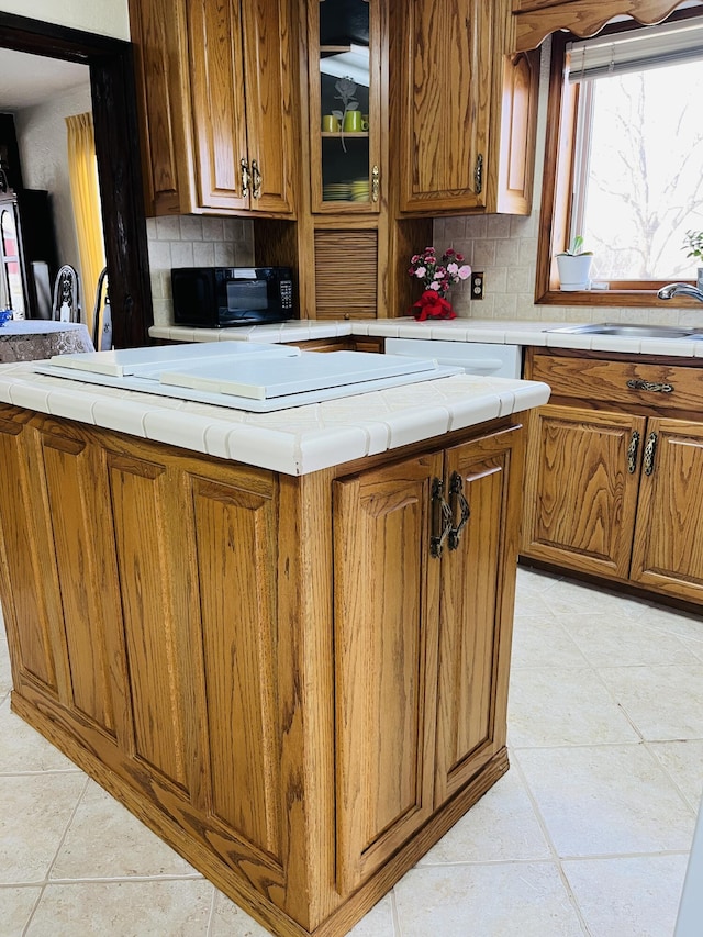 kitchen featuring tasteful backsplash, sink, a center island, and light tile patterned floors