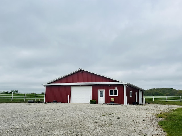 detached garage featuring a rural view and fence