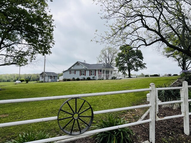 exterior space with a rural view, fence, and a front yard