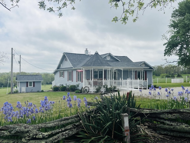 view of front facade with covered porch, a chimney, roof with shingles, and a front lawn