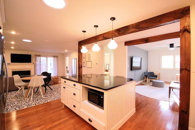 kitchen with pendant lighting, white cabinetry, beam ceiling, and dark wood-type flooring