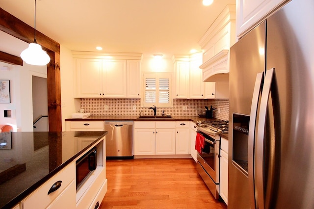 kitchen featuring pendant lighting, white cabinetry, sink, dark stone counters, and stainless steel appliances