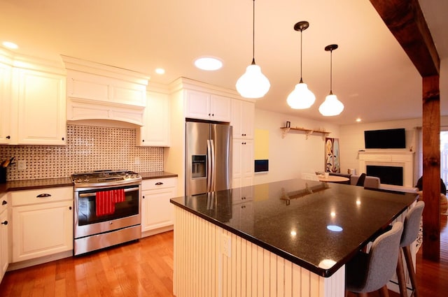 kitchen featuring a breakfast bar, pendant lighting, white cabinets, stainless steel appliances, and light hardwood / wood-style flooring