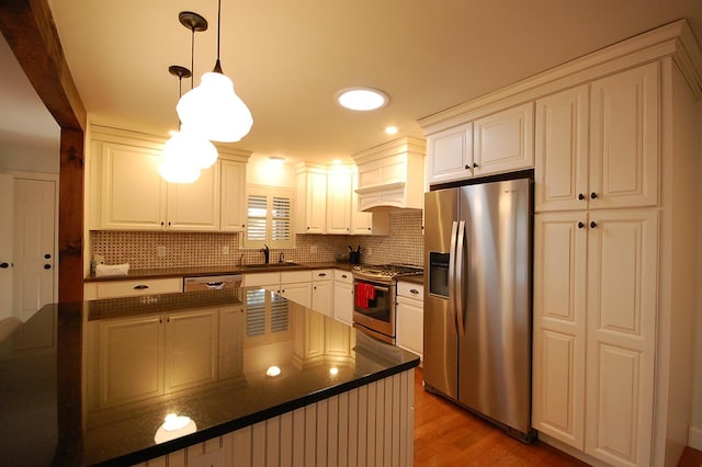 kitchen with sink, decorative light fixtures, light hardwood / wood-style flooring, appliances with stainless steel finishes, and decorative backsplash