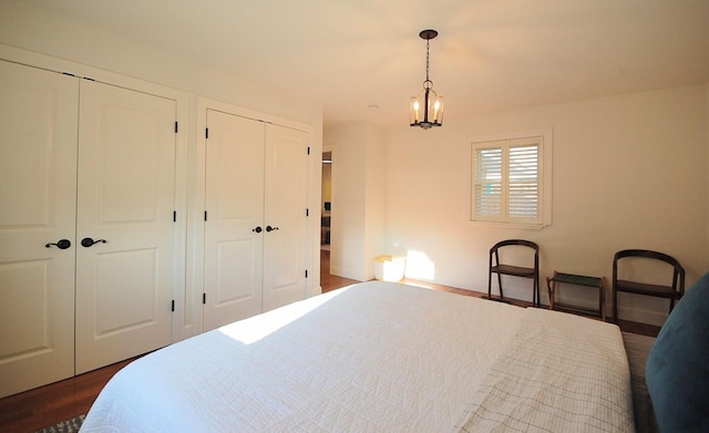 bedroom featuring a chandelier, two closets, and dark hardwood / wood-style flooring