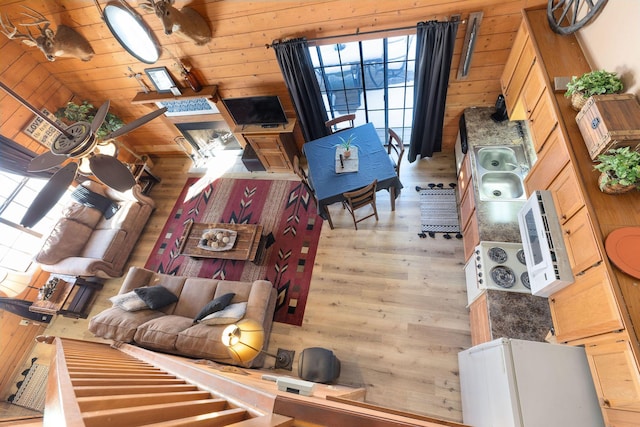 living room featuring high vaulted ceiling, ceiling fan, and wood walls