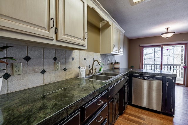 kitchen featuring sink, dishwasher, wood-type flooring, a textured ceiling, and decorative backsplash