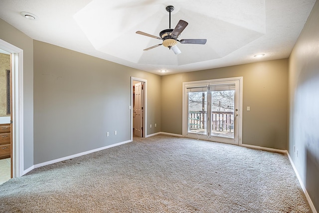 carpeted spare room featuring a raised ceiling and ceiling fan