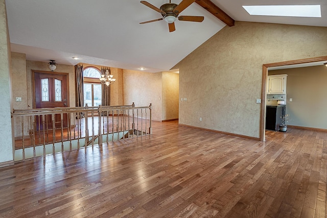 living room with vaulted ceiling with skylight, ceiling fan with notable chandelier, and light hardwood / wood-style flooring