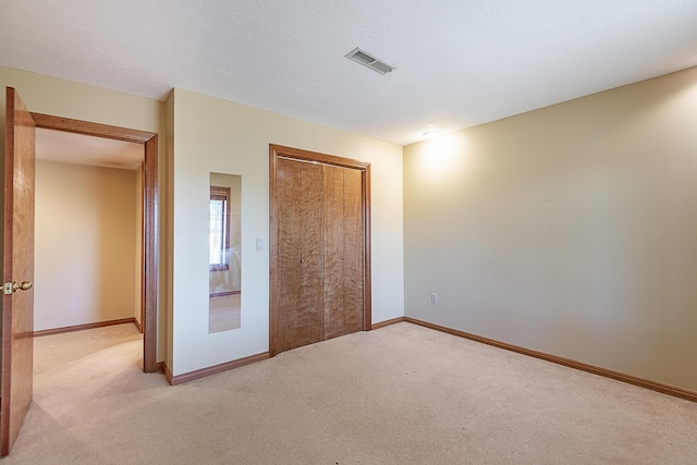 unfurnished bedroom featuring light carpet and a closet