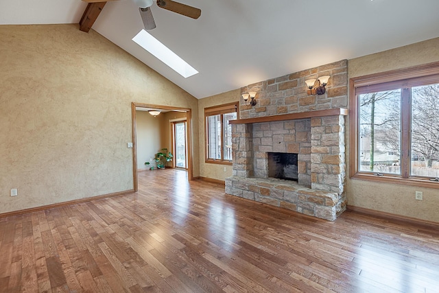 unfurnished living room featuring a skylight, beam ceiling, a fireplace, and light wood-type flooring