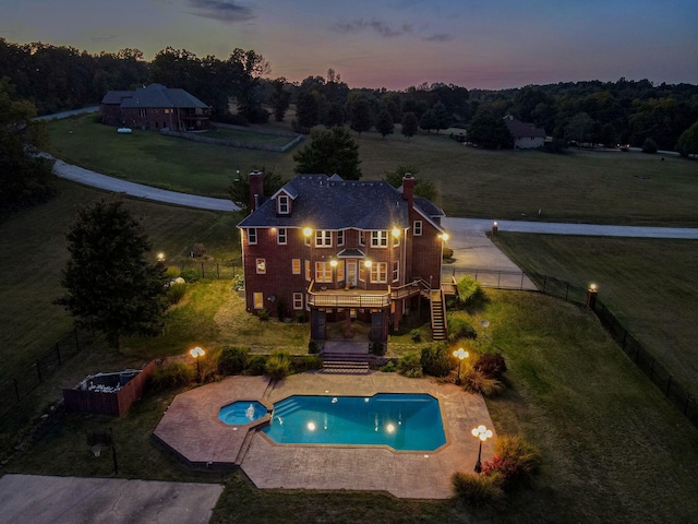 pool at dusk with a patio and an in ground hot tub