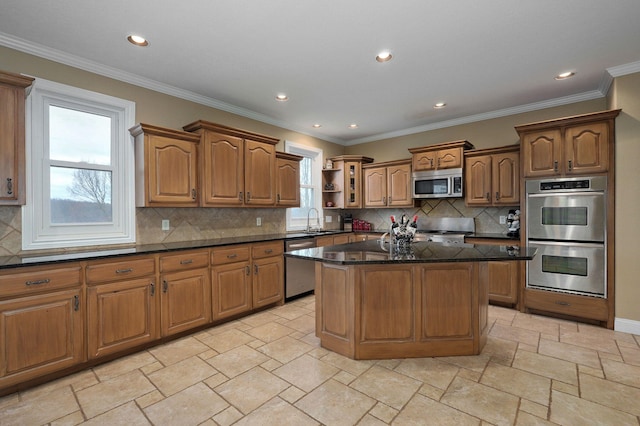 kitchen featuring ornamental molding, appliances with stainless steel finishes, a center island, and sink