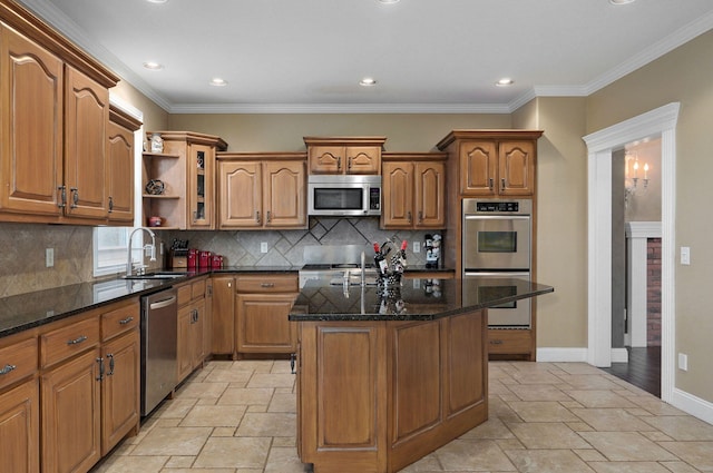 kitchen with sink, crown molding, dark stone countertops, appliances with stainless steel finishes, and a kitchen island