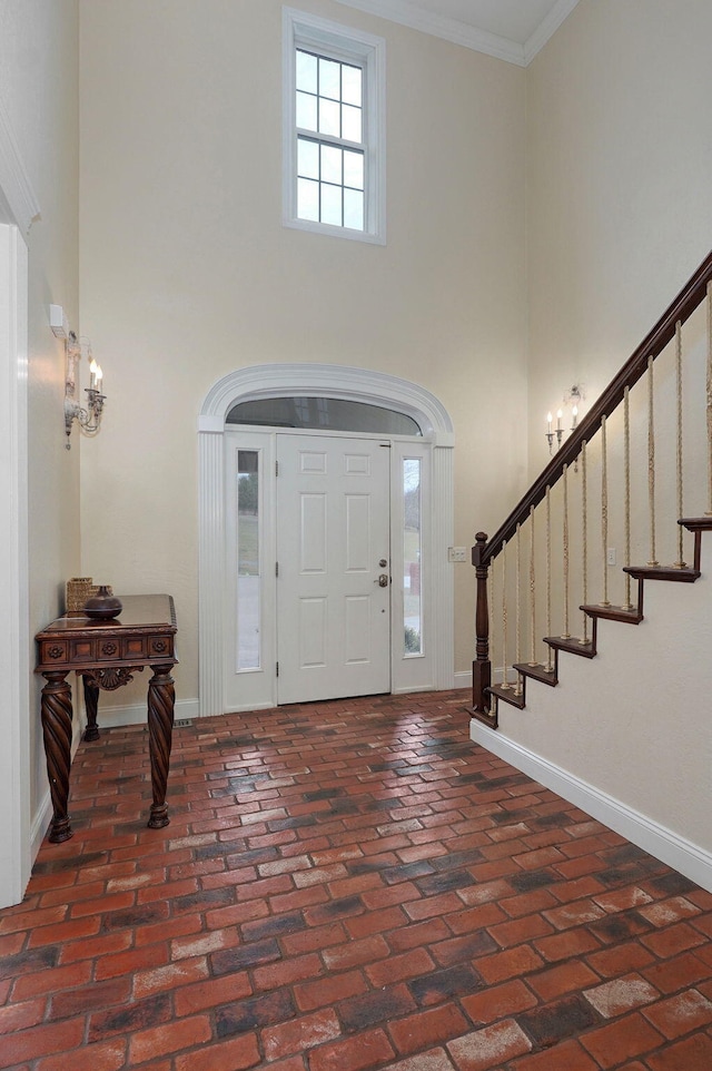 entrance foyer featuring crown molding and a towering ceiling