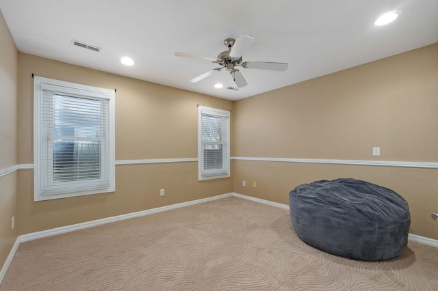 living area featuring light carpet and ceiling fan