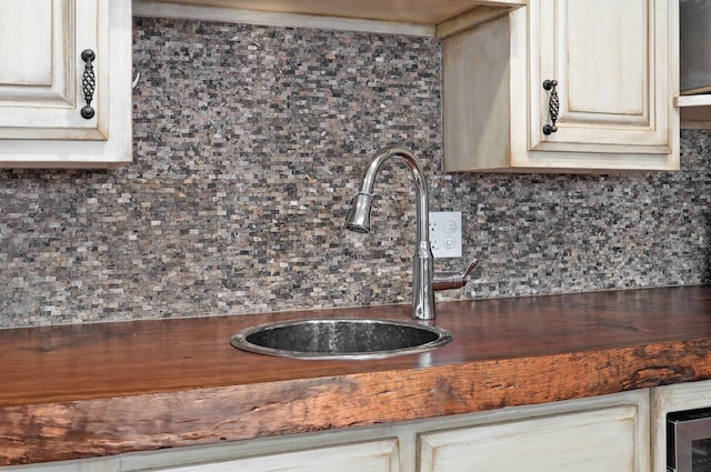 interior details with tasteful backsplash, cream cabinets, and sink