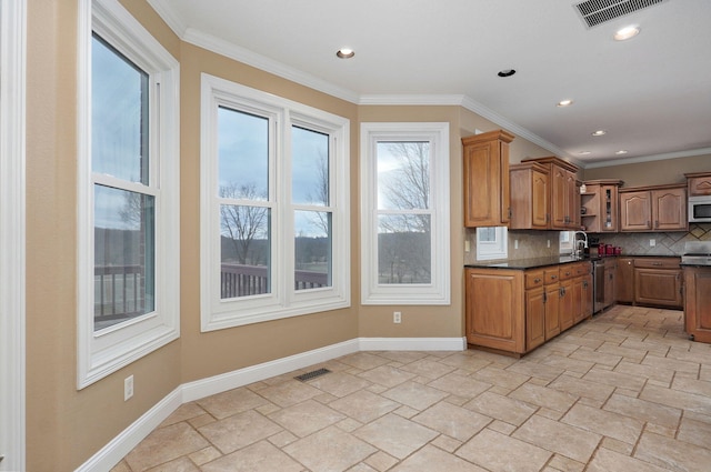 kitchen with tasteful backsplash, ornamental molding, appliances with stainless steel finishes, and sink