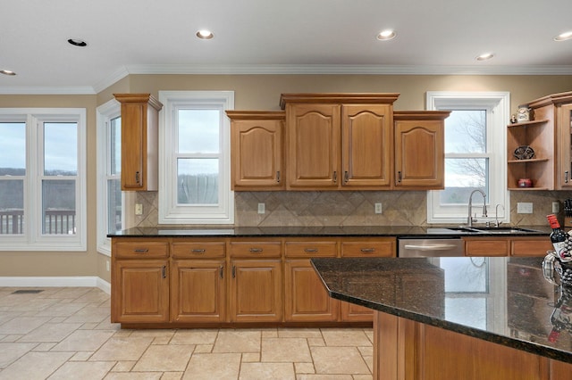 kitchen with crown molding, dark stone counters, sink, and a wealth of natural light