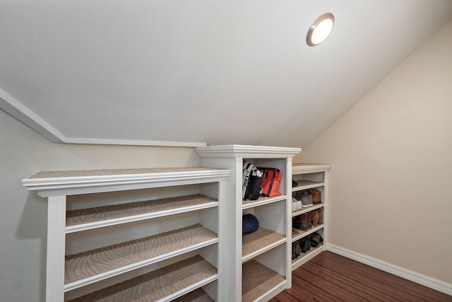 walk in closet with dark wood-type flooring and lofted ceiling