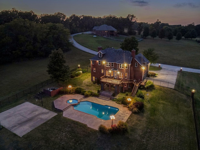 pool at dusk featuring a water slide, a yard, a deck, and a patio area