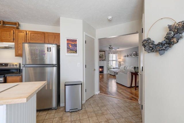 kitchen with butcher block countertops, stainless steel appliances, a textured ceiling, and ceiling fan