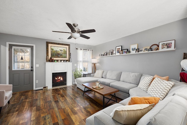 living room with ceiling fan, a textured ceiling, and dark hardwood / wood-style flooring