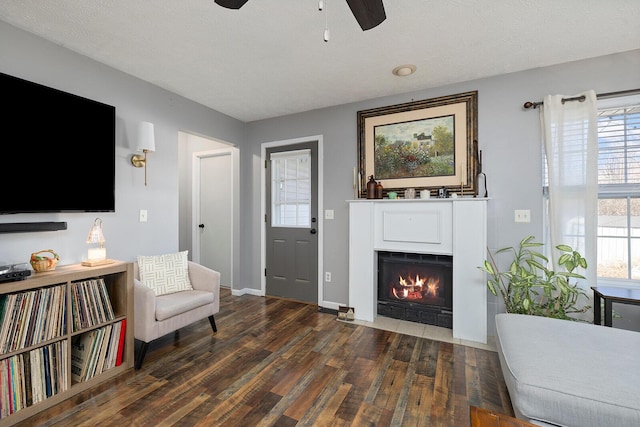 sitting room featuring ceiling fan, dark wood-type flooring, and a textured ceiling