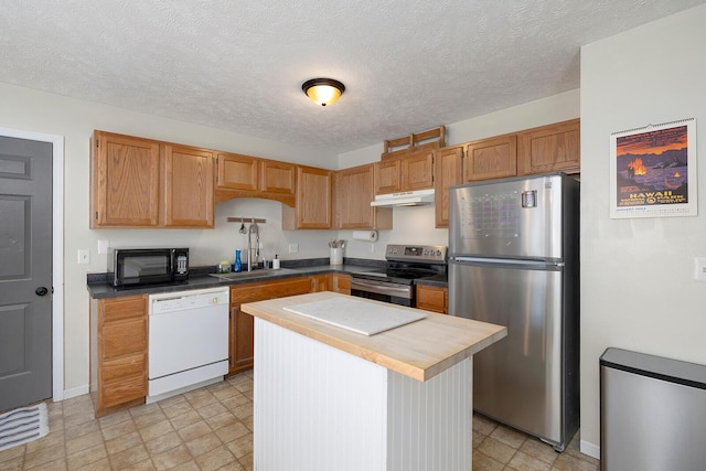 kitchen with sink, a kitchen island, a textured ceiling, and appliances with stainless steel finishes