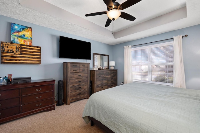 bedroom with light carpet, a tray ceiling, and ceiling fan