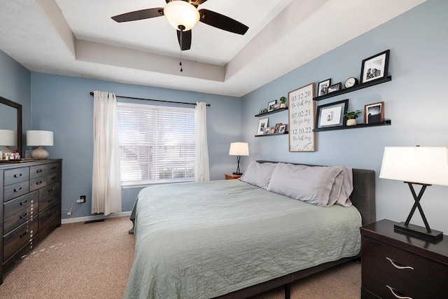 bedroom featuring light colored carpet, ceiling fan, and a tray ceiling