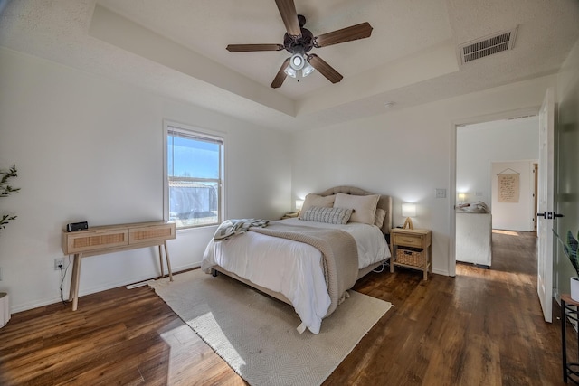 bedroom featuring ceiling fan, dark hardwood / wood-style floors, and a raised ceiling