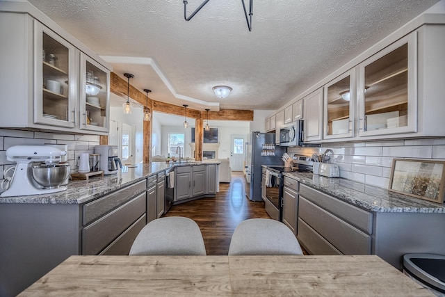 kitchen with pendant lighting, decorative backsplash, gray cabinets, and stainless steel appliances