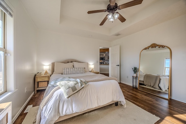 bedroom featuring a tray ceiling, dark wood-type flooring, and ceiling fan