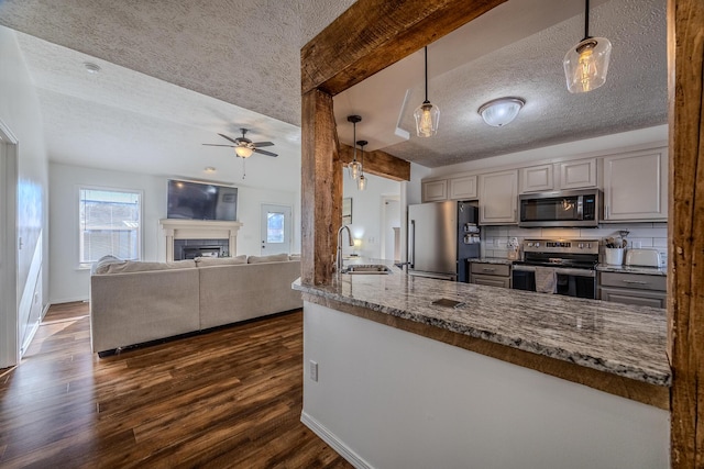 kitchen featuring hanging light fixtures, light stone countertops, sink, and appliances with stainless steel finishes