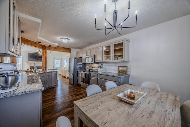 dining area featuring dark wood-type flooring, a chandelier, sink, and a textured ceiling