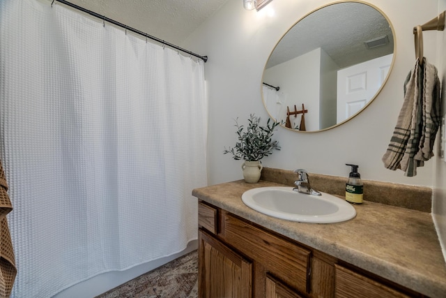 bathroom with vanity, a textured ceiling, and walk in shower