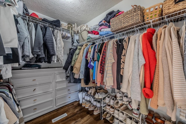 walk in closet with dark wood-type flooring